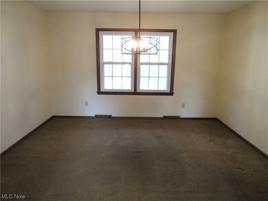 Unfurnished room featuring dark carpet and a notable chandelier