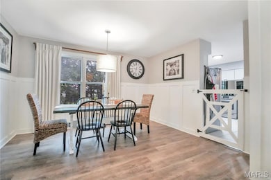 Dining space with a decorative wall, wainscoting, and wood finished floors