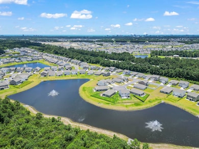Aerial view of property and surrounding area featuring nearby suburban area and a large body of water