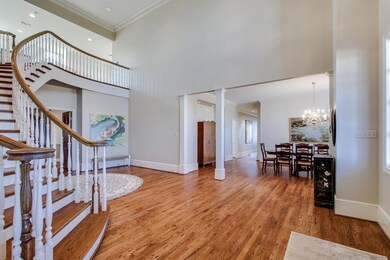 Dining room houses a very large and long dining table. The open and tall ceilings create a spacious feel.