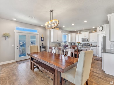 Dining space with light wood-type flooring, recessed lighting, a textured ceiling, and a chandelier