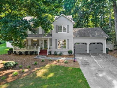 Traditional home featuring a porch, an attached garage, roof with shingles, concrete driveway, and a front yard