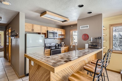Kitchen with tile counters, visible vents, applian