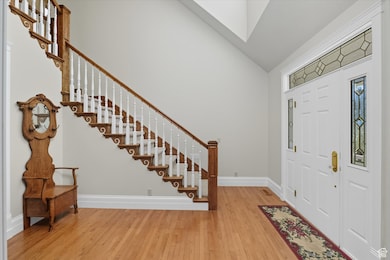Entryway with light wood finished floors, stairs, and high vaulted ceiling