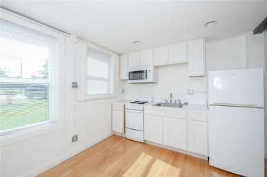 Kitchen with a sink, white appliances, light wood