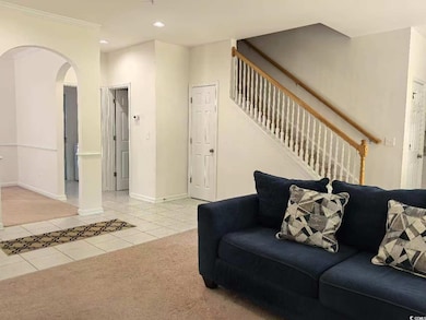 Tiled living area featuring arched walkways, stair