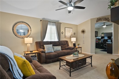 Living room featuring ceiling fan, light colored carpet, and vaulted ceiling