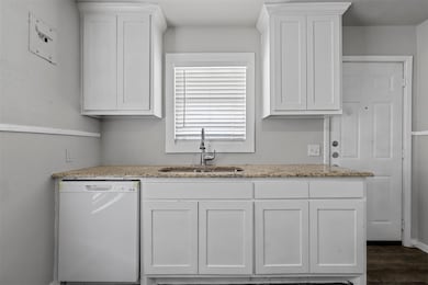 Kitchen with a sink, light stone countertops, dish