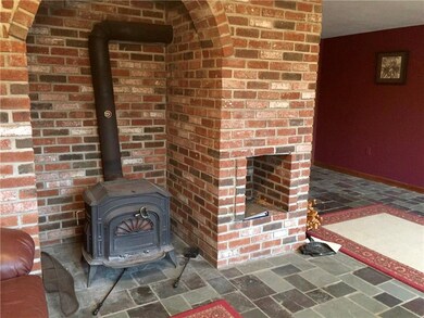 Den wood stove and brick fireplace.