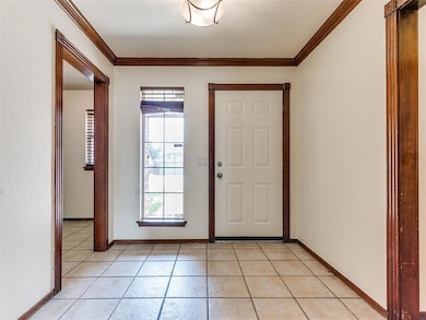 Tiled entryway featuring crown molding and a healt