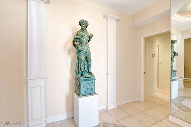 Corridor with light tile patterned floors, baseboards, and ornate columns