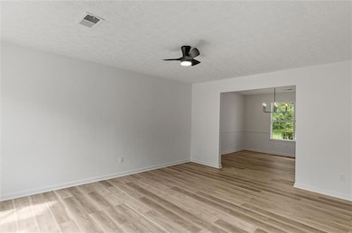 Unfurnished room with light wood-style flooring, a textured ceiling, a ceiling fan, and a chandelier