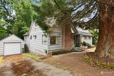 One car garage on the left with plenty of parking in front. Steps to the right of the garage lead into the kitchen. The large sycamore tree was planted by seed from the sellers Dad.