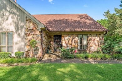 View of front facade featuring stone siding, roof with shingles, and a front yard