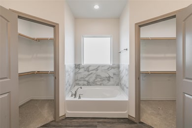 Bathroom with a walk in closet and a garden tub