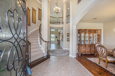 Inviting rotunda foyer with curved, wrought iron staircase and high ceiling.