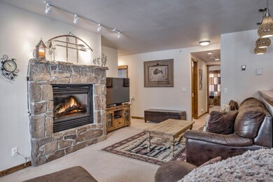 Carpeted living room featuring a stone fireplace a
