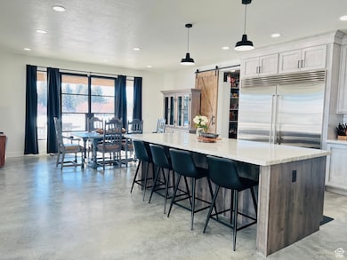Kitchen with a textured ceiling, a barn door, built in fridge, a kitchen island, and finished concrete flooring