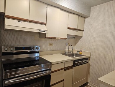 Kitchen featuring stainless steel electric range, wallpapered walls, under cabinet range hood, light countertops, and white cabinetry