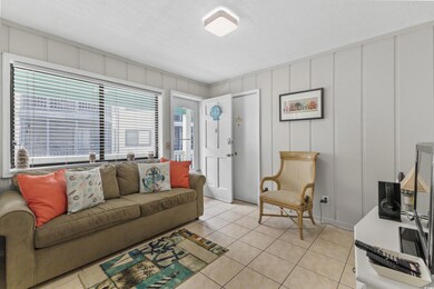 Living area with light tile patterned floors, a decorative wall, and a textured ceiling