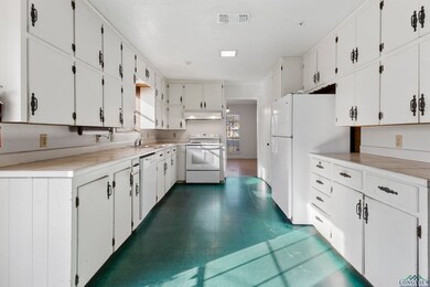 Kitchen with white appliances, white cabinetry, an
