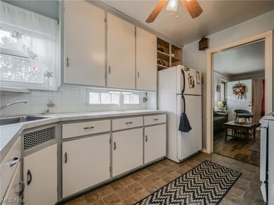 Kitchen featuring dark tile flooring, white cabinetry, white refrigerator, and ceiling fan