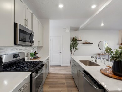 Kitchen featuring stainless steel appliances, gray cabinets, light stone counters, light wood-type flooring, and recessed lighting