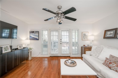Living room with wood finished floors, french doors, and a ceiling fan