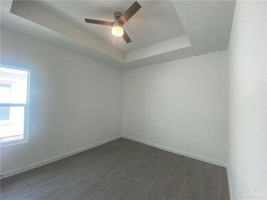 Spare room with a raised ceiling, a ceiling fan, and dark wood-style flooring