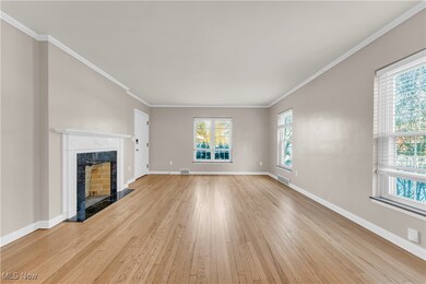 Unfurnished living room with crown molding, a high end fireplace, and light wood-type flooring
