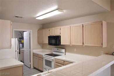 Kitchen with white appliances, visible vents, tile