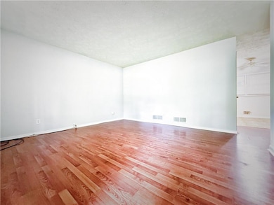 Unfurnished room featuring wood finished floors, ceiling fan, a textured ceiling, and baseboards