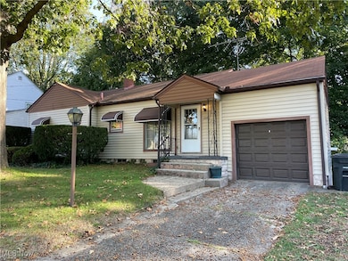View of front of home featuring a front lawn, a chimney, an attached garage, and driveway