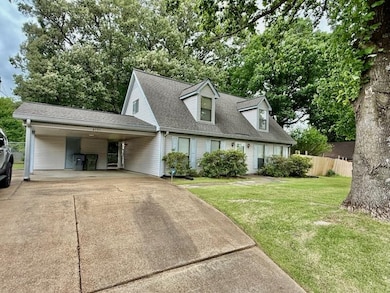 New england style home with driveway, an attached carport, and roof with shingles