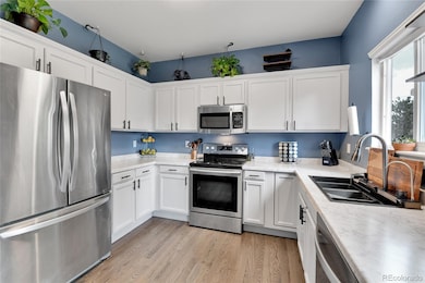 Bright kitchen with hardwood floors, and stainless steel appliances.