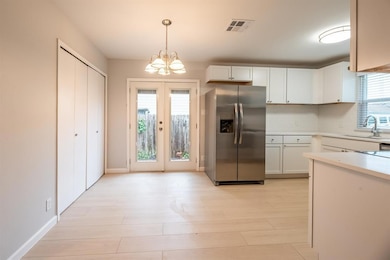 Kitchen with stainless steel fridge with ice dispenser, light countertops, white cabinetry, pendant lighting, and a chandelier
