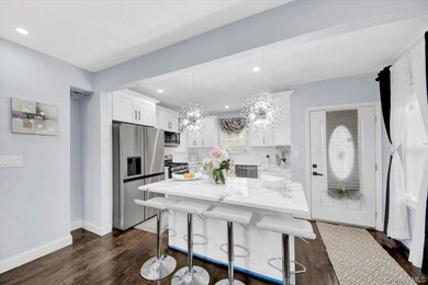 Kitchen with appliances with stainless steel finishes, white cabinets, a breakfast bar area, a center island, and light stone countertops