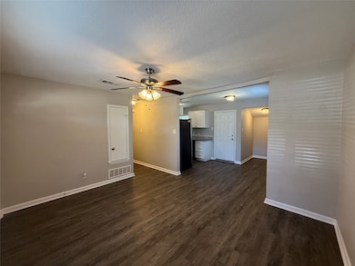 Unfurnished living room featuring dark wood-style floors, a textured ceiling, and ceiling fan