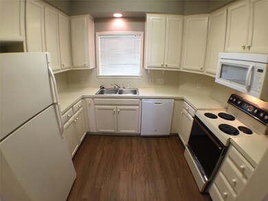 Kitchen with white cabinets, white appliances, a 
