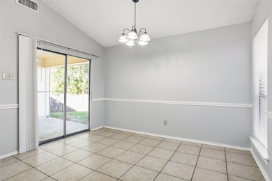 Spare room featuring vaulted ceiling, light tile patterned flooring, a chandelier, and a textured ceiling