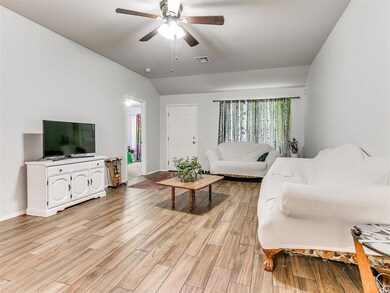 Living room with vaulted ceiling, ceiling fan, and light hardwood / wood-style floors