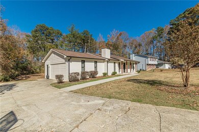 View of front of house featuring a front lawn, concrete driveway, covered porch, a chimney, and an attached garage