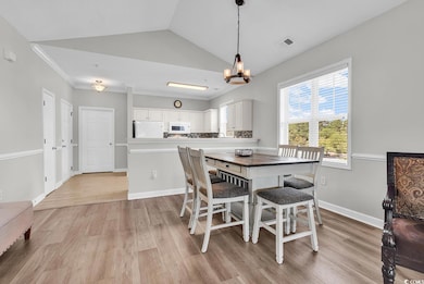 Dining room featuring light wood-style flooring, a chandelier, lofted ceiling, and crown molding