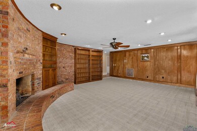 Unfurnished living room featuring a textured ceiling, light colored carpet, ceiling fan, and a brick fireplace