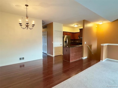 Kitchen featuring open floor plan, dark countertops, hanging light fixtures, stainless steel refrigerator with ice dispenser, and a chandelier