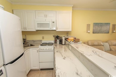 Kitchen with white appliances, a sink, white cabinets, ornamental molding, and open floor plan