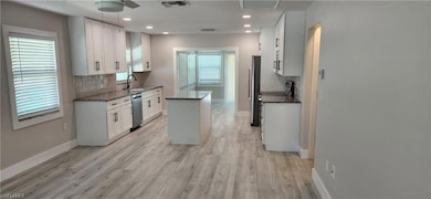 Kitchen featuring white cabinetry, dark stone coun