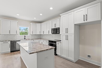 Kitchen with white cabinets, a center island, ligh