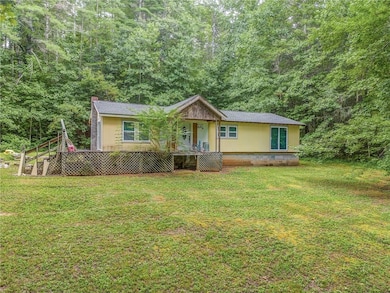 View of front of property featuring a front yard, crawl space, a chimney, and a shingled roof