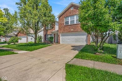 traditional-style home with brick siding, a garage, concrete driveway, and a front lawn